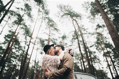 Gorgeous Newlywed Bride And Groom Posing In Pine Forest Near Retro Car