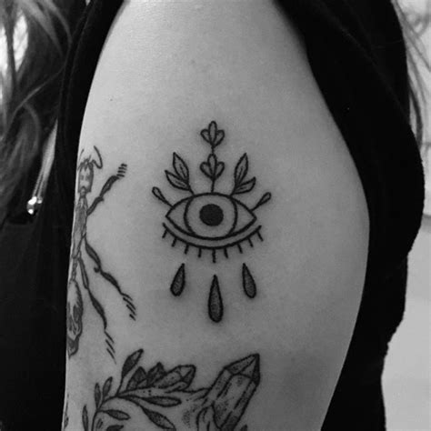 A Womans Arm With An Evil Eye And Flowers On The Left Side Of Her Arm