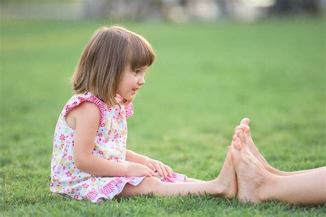 Little Girl Measuring Her Tiny Feet With Her Older Sister By Stocksy