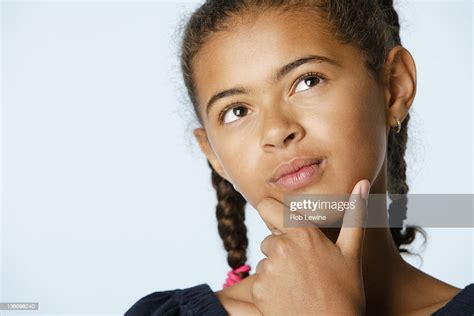 Studio Portrait Of Girl With Hand On Chin Looking Up High Res Stock