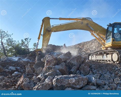Excavator Is Moving A Rock Boulders During Road Construction On The