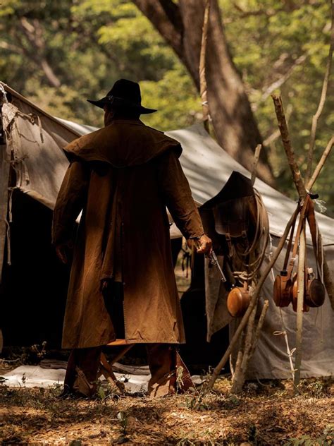 A Senior Cowboy Standing With A Gun To Guard The Safety Of The Camp In