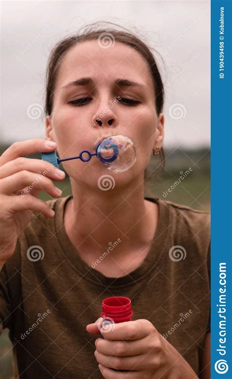 The Girl Blows Soap Bubbles A Young Woman Sits In Nature And Blows