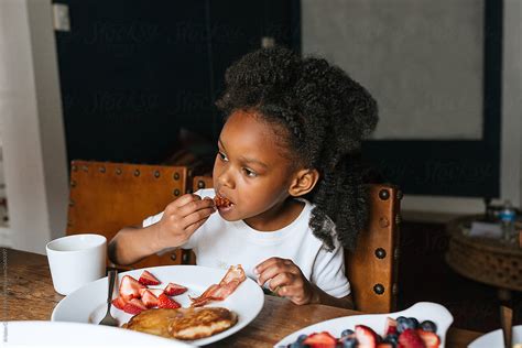 An African American Girl Eating Breakfast At The Table By Stocksy Contributor Kristen