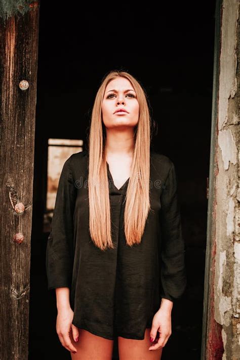 Sensual Blonde Girl In Black Shirt Waiting Near A Door Stock Image