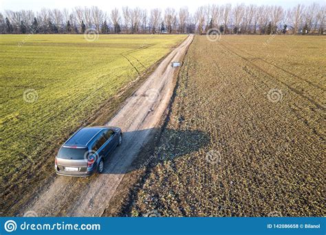 Aerial View Of Car Driving By Straight Ground Road Through Green Stock