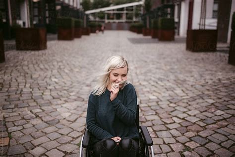 attractive woman with toothy smile on wheelchair at city street by stocksy contributor chris