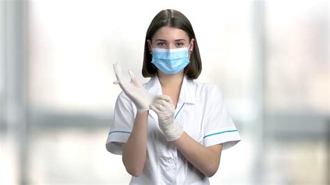 Lady doctor putting on protective gloves. Beautiful female doctor in ...
