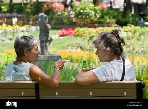 Two Mature Women In The Park Having An Animated Conversation Beautiful Flower Garden Stock Photo