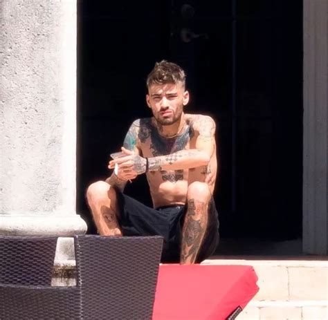 Shirtless Zayn Malik Looks Downcast As He Stares Into The Distance And Smokes Cigarette After