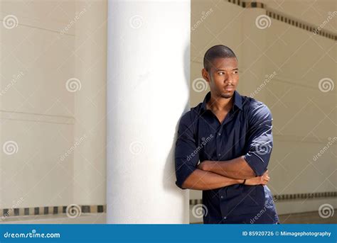 Serious Young Black Man Leaning Against Wall With Arms Crossed Stock