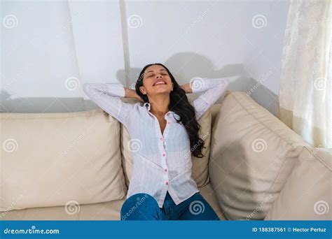 Happy Hispanic Woman Resting Comfortably Sitting On A Couch In The