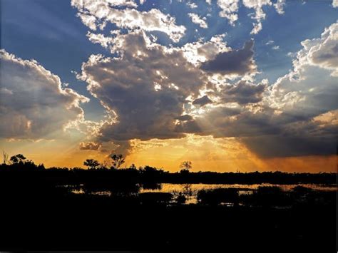 Body Of Water Near Silhouette Of Mountain Under White Clouds During