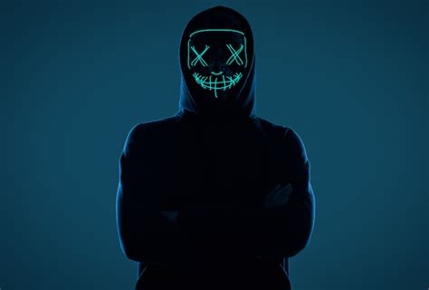 Premium Photo Anonymous Man In Black Hoodie Hiding His Face Behind A Neon Mask