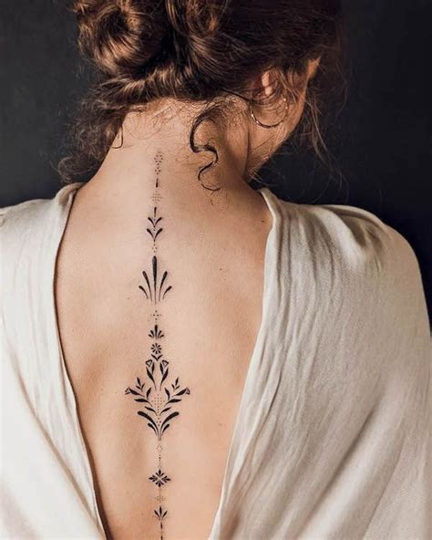 The Back Of A Woman S Neck With An Intricate Tattoo Design On Her Left Side