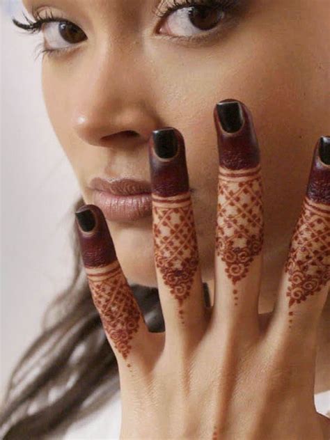 A Woman Holding Her Hands Up To Her Face With Henna Tattoos On Its Fingers