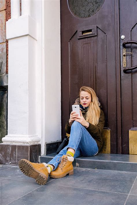 Beautiful Woman Using Phone On Doorstep Del Colaborador De Stocksy Danil Nevsky Stocksy