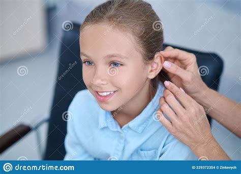 Happy Girl And Doctors Hands Putting On Hearing Aid Stock Photo Image