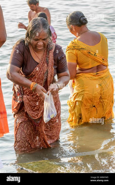 An Indian Hindu Woman Wearing A Sari Performs An Early Morning Bathing Ritual In The River