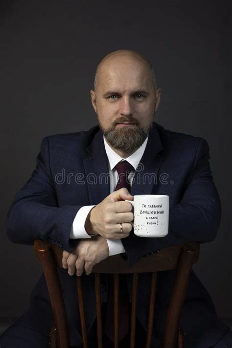 A Man Sitting On A Chair With A Tea Cup In His Hand Stock Image