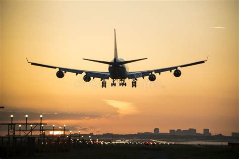 Airplane Landing With An Orange Sky At The Background Stock Photo