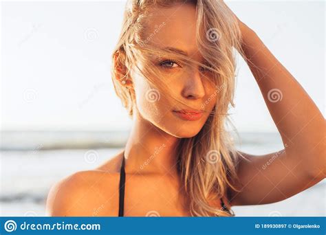 Headshot Of Beautiful Blonde Slim Girl In A Black Bikini On The Beach The Ocean Against The Sun