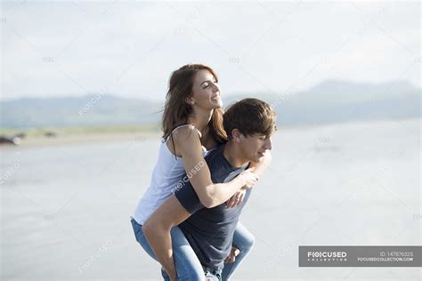 Man Giving Piggyback Ride To Female Friend — Smiling Holiday Stock