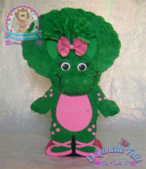 A Green Stuffed Animal With A Pink Bow On Its Head And Legs Sitting