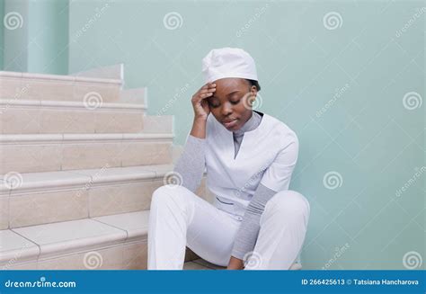 A Frustrated African American Nurse Is Sitting In A Hospital Corridor