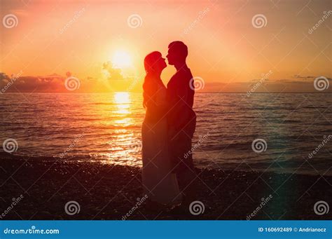 Two Young Lovers Standing On A Beach And Looking To Each Other Stock