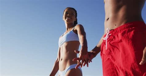 African American Couple In Swimwear Smiling And Holding Hands On The Beach Stock Video Envato