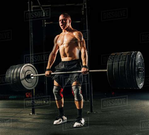 Man Lifting Heavy Barbell In Gymnasium Stock Photo Dissolve