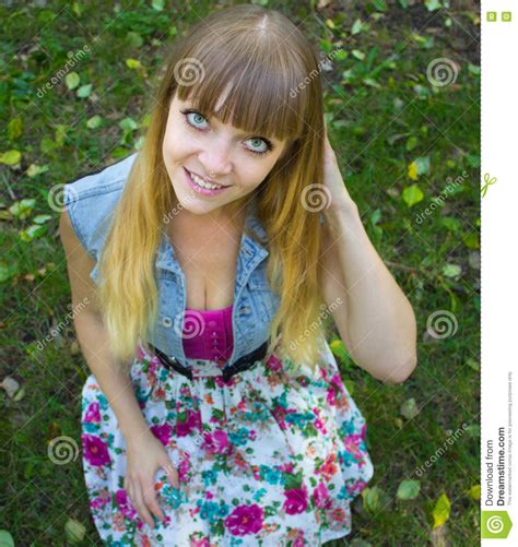 Beauty Blonde Teen Girl With Big Eyes Sitting On Grass