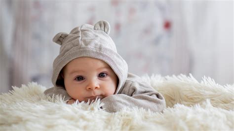 Cute Baby Is Lying Down On Sandal Woolen Bed Wearing Bunny Cap 4k Cute