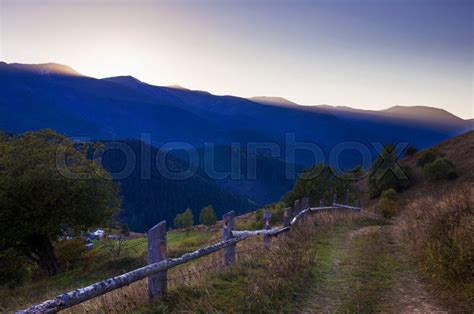 The Road On Hill And Wooden Fence On Mountain Background Stock Photo
