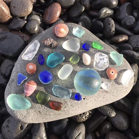 A Rock Covered In Sea Glass Sitting On Top Of Some Rocks