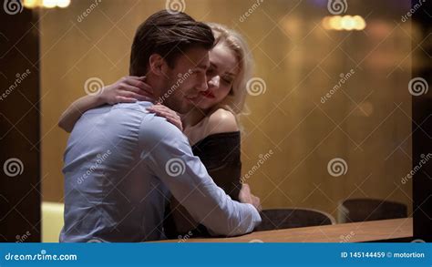 Young Man Hugging And Petting Beautiful Blonde At Lounge Bar Evening