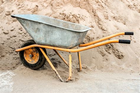 Premium Photo Construction Wheelbarrow Close Up Against A Pile Of Sand