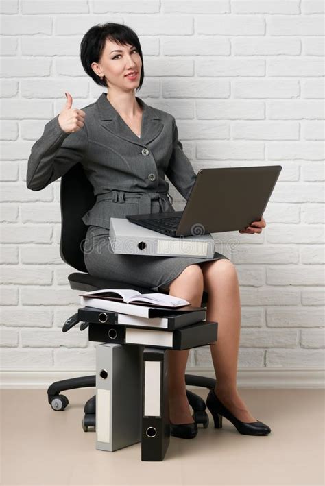 Business Woman With Laptop And Folders Dressed In A Gray Suit Poses In