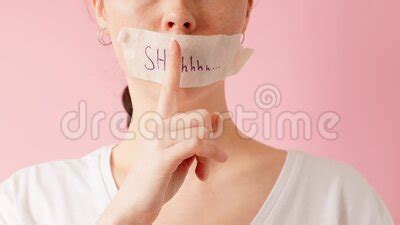 A Woman Turns And Shows Her Mouth Taped Shut Puts Her Index Finger To