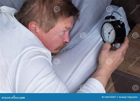 An Adult Man Wakes Up To The Alarm Clock On The Bed Stock Image Image