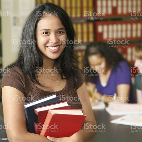 Young Hispanic College Student Holding Books In Campus Library Stock