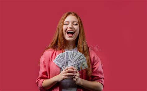 rich excited ginger woman with cash money usd currency dollars banknotes on pink stock image