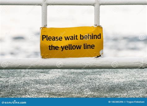 Yellow Sign That Says Please Wait Begind The Yellow Line Stock Photo