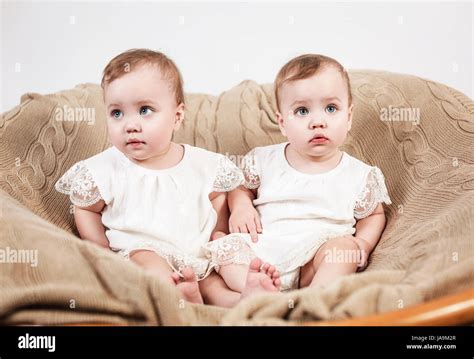 Two Adorable Baby Twin Girls Cute Identical Twins Sitting On The Coach