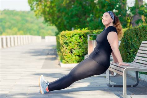 el retrato de la mujer regordeta feliz activa realiza ejercicios en el parque foto de archivo