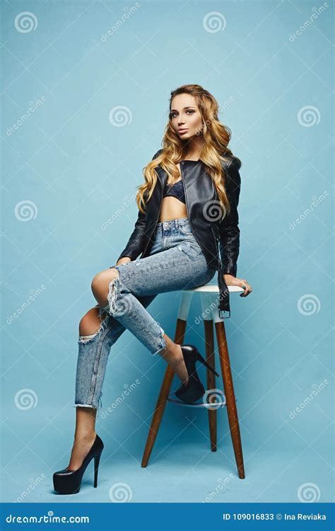 schönes sexy modernes blondes halb nacktes mädchen in der lederjacke und jeans am blauen