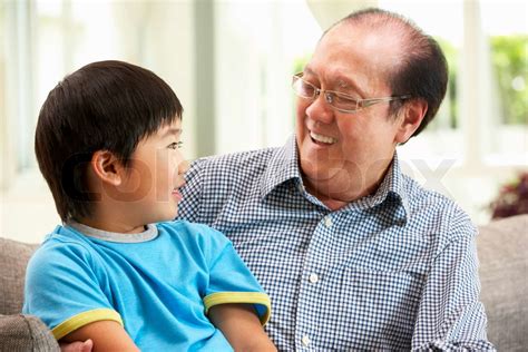 Chinese Grandfather And Grandson Relaxing On Sofa At Home Stock Image Colourbox