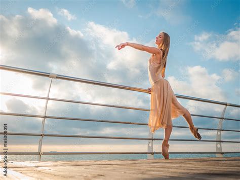 Dancing Ballerina In Beige Silk Dress And Pointe On Embankment Above