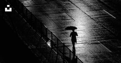 A Person Walking Down A Sidewalk With An Umbrella Photo Free Lighting